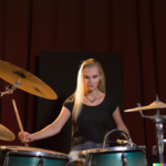 DALL·E-2023-02-01-18.52.32-BEAUTIFUL-BLONDE-WOMAN-PLAYING-DRUMS-ON-STAGE