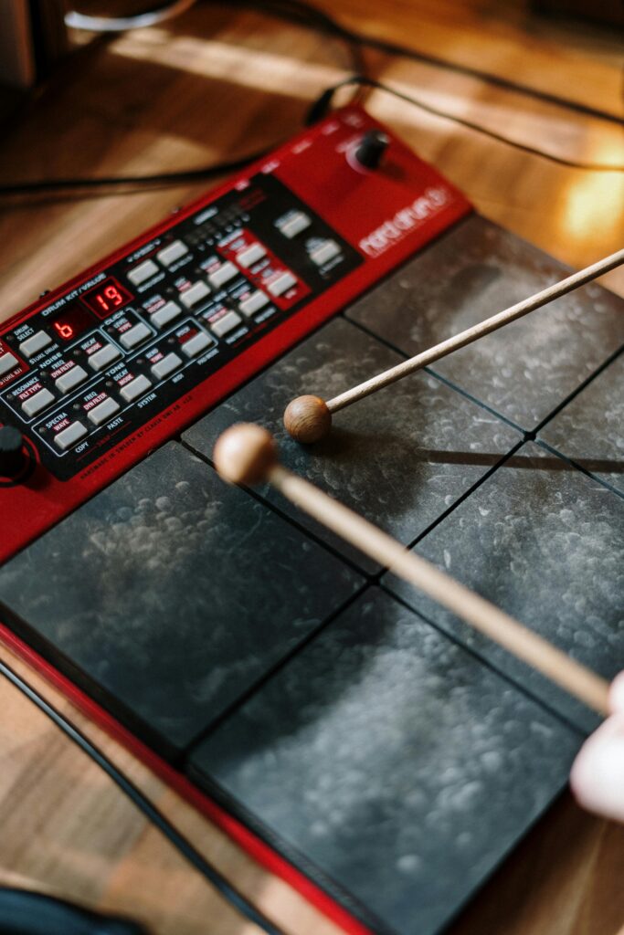 Detailed shot of an electronic drum pad with two drumsticks in motion.